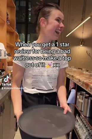 Daniella Claeys laughing while wearing the T-shirt at work, holding a tray