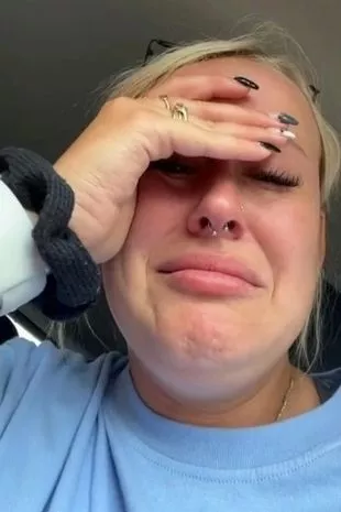 A woman in distress holding her head after seeing her botched tattoo.